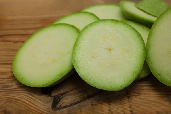 Sliced green zucchini on wooden background, copy space. Healthy food, green vegan diet, raw recipes.