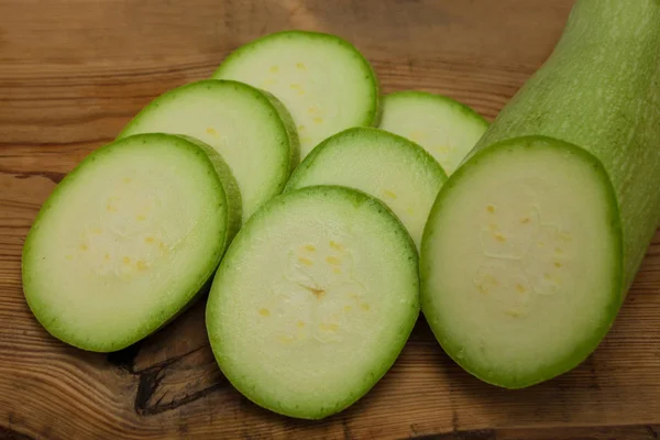 Sliced green zucchini on wooden background, copy space. Healthy food, green vegan diet, raw recipes. — Stock Photo, Image