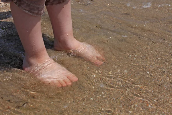 A baby try to step in to the sea water at the first time in a sunny day. With blurry sea background. Stock Picture