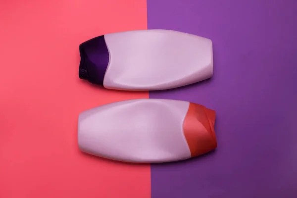Beauty, decorative cosmetics bottles. Pink and purple colors background, flat lay, top view, minimalistic pop-art style