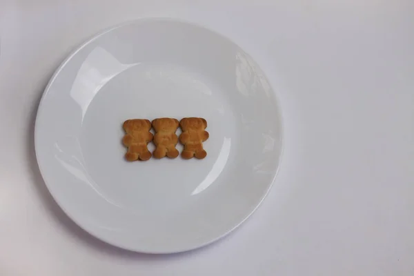 Bonito ursos biscoitos na placa redonda cerâmica isolada sobre fundo branco. Vista de cima, flat lay . — Fotografia de Stock