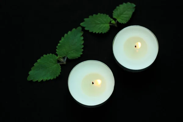 White burning tealight candles on black background. Beauty, SPA treatments, massage therapy and relax concept.