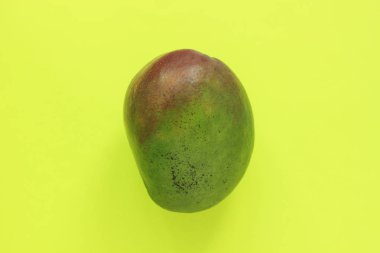 Olgun Yeşil ve Kırmızı Mango Sarı Arka Plan üzerinde. Tarz Yaratıcı Görüntü. Kopyalama alanı, minimalist stil.