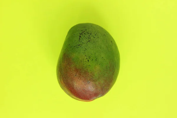 Ripe Green and Red Mango on Yellow Background. Styled Creative Image. Copy space, minimalistic style.