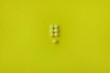Sarı bir arka planda ünlem işareti şeklinde Pills. Düz yatıyordu, üst görünüm, minimalist tarzı.