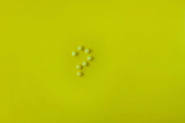Pillen in Fragezeichen auf gelbem Hintergrund. flache Lage, Draufsicht, minimalistischer Stil. — Stockfoto