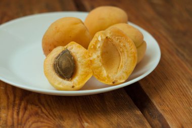 Ahşap arka plan üzerinde beyaz bir tabak üzerinde olgun taze kayısı meyve. Kopya alanı, delisious sağlıklı gıda.