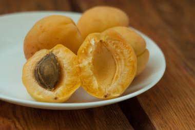 Ahşap arka plan üzerinde beyaz bir tabak üzerinde olgun taze kayısı meyve. Kopya alanı, delisious sağlıklı gıda.