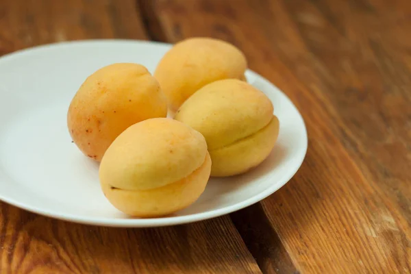Зрізати свіжі абрикосові фрукти на білій тарілці на дерев'яному тлі. Копіювати простір, смачна здорова їжа . — стокове фото