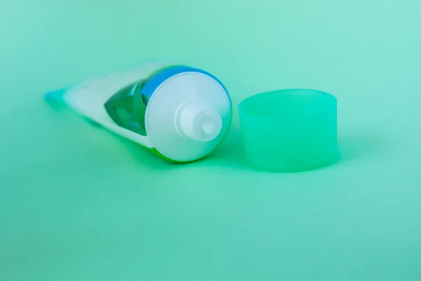 Tube with cream on a mint background, cosmetics care concept, minimalistic style.