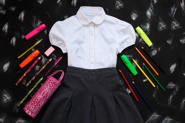 Camisa blanca, falda gris y artículos de papelería sobre fondo negro. El primero de septiembre, nuevo año escolar . — Foto de Stock