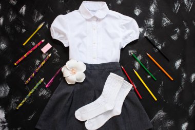 Beyaz gömlek, gri etek ve siyah arka plan üzerinde kırtasiye malzemeleri. Eylül'ün ilk, yeni öğretim yılı.