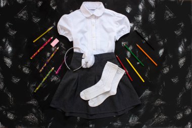 Beyaz gömlek, gri etek ve siyah arka plan üzerinde kırtasiye malzemeleri. Eylül'ün ilk, yeni öğretim yılı.