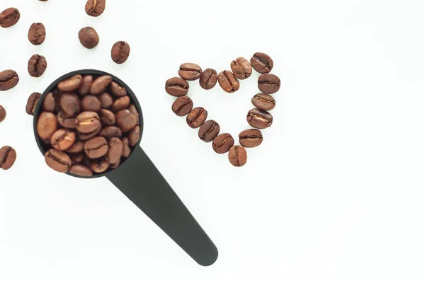 Brown roasted coffee beans in a black measuring spoon on a white background isolated. — Stock Photo, Image