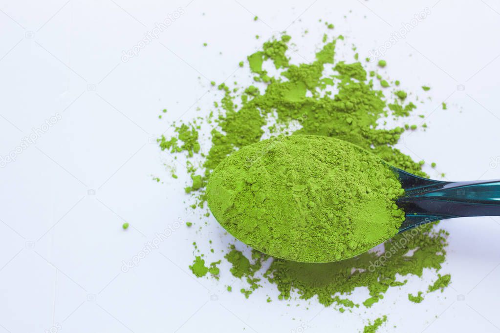 A spoon with powdered matcha green tea, isolated on light background, copy space, top view.