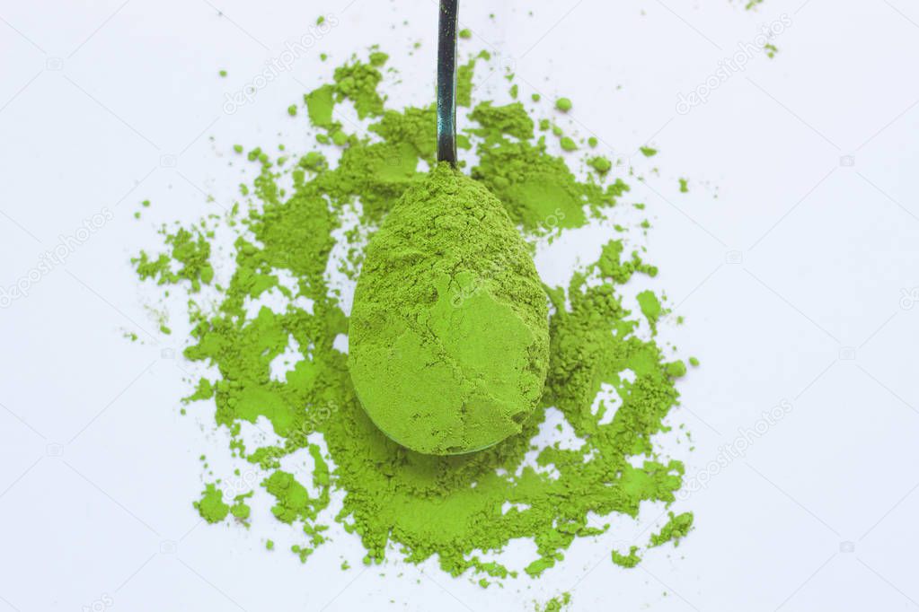 A spoon with powdered matcha green tea, isolated on light background, copy space, top view.