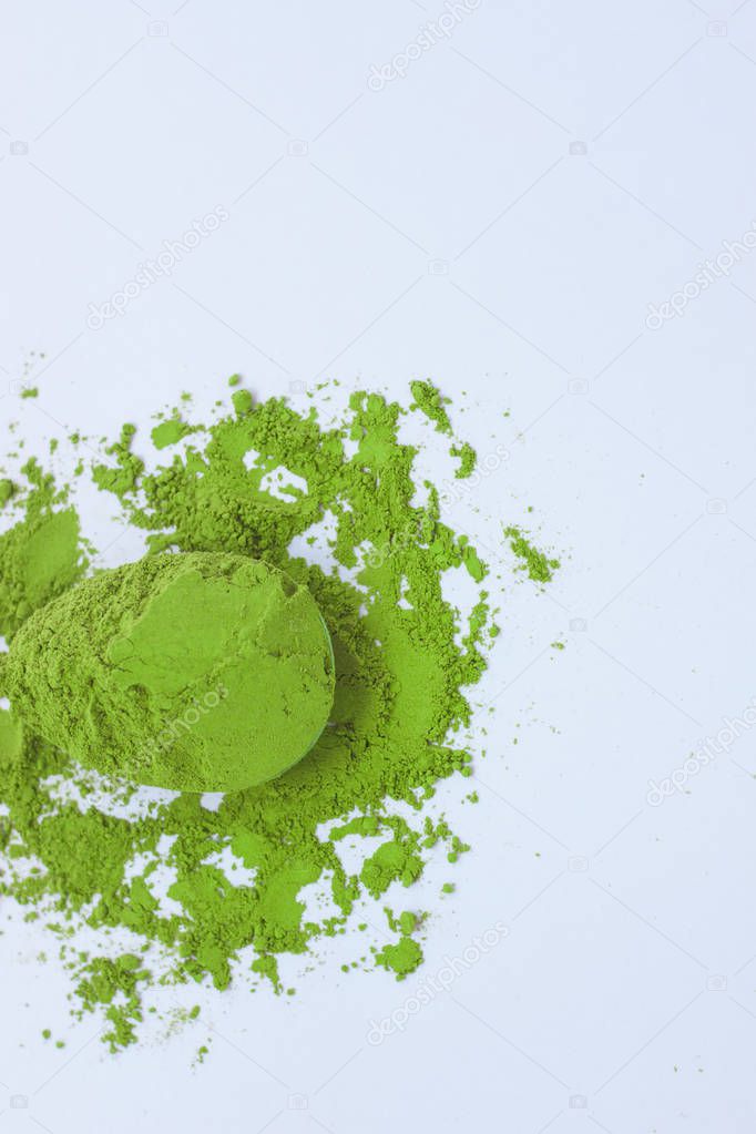 A spoon with powdered matcha green tea, isolated on light background, copy space, top view.