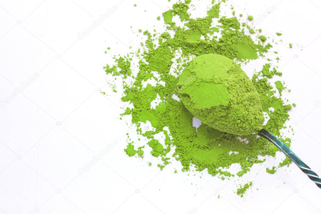 A spoon with powdered matcha green tea, isolated on white background, copy space, top view.