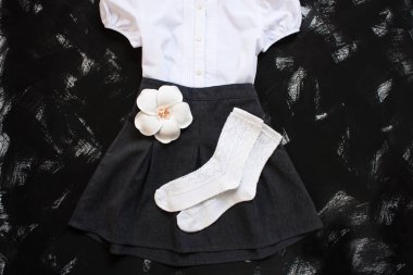 Beyaz gömlek, çorap ve siyah arka planda koyu denim etek ile okul üniforması. Flatlay, üst görünüm, kopya alanı.