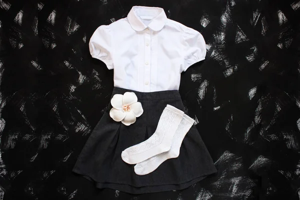 Uniforme escolar con camisa blanca, calcetines y falda de mezclilla oscura sobre fondo negro. Flatlay, vista superior, espacio para copiar . — Foto de Stock