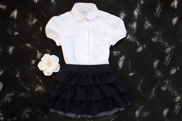 Uniforme escolar con camisa blanca, calcetines y falda de mezclilla oscura sobre fondo negro. Flatlay, vista superior, espacio para copiar . — Foto de Stock