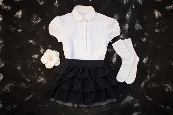 Beyaz gömlek, çorap ve siyah arka planda koyu denim etek ile okul üniforması. Flatlay, üst görünüm, kopya alanı.