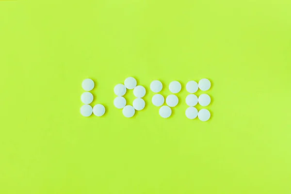 Pills in a shape of a word Love on a yellow background. Flat lay, top view, minimalistic style. — Stock Photo, Image