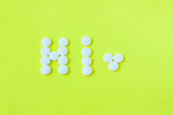 Pillen in Form eines Wortes hallo auf gelbem Hintergrund. flache Lage, Draufsicht, minimalistischer Stil. — Stockfoto