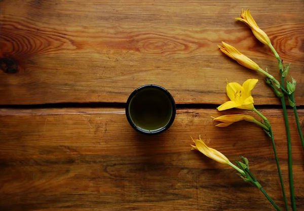 美しい黄色のユリと暗褐色の木製の背景に緑茶のボウル. — ストック写真