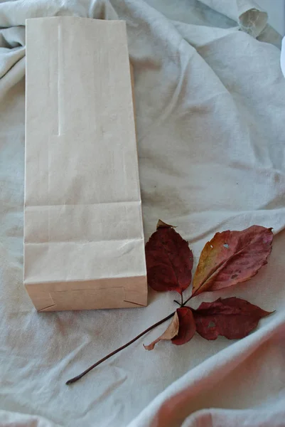 Bolsas de papel Kraft con hojas de otoño sobre fondo de tela de lino vintage . — Foto de Stock