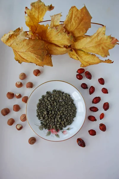 Ginseng oolong Chinese tea on a white plate with nuts, autumn leaves — Stock Photo, Image