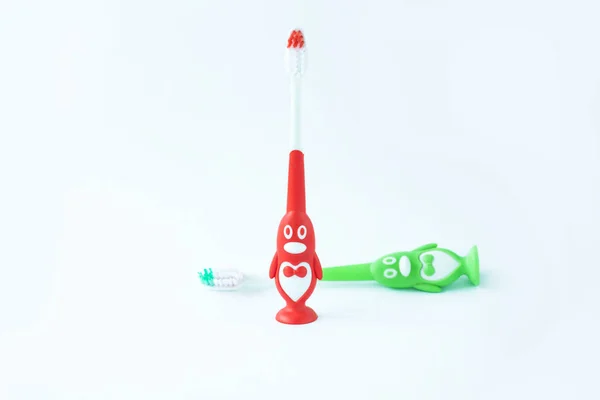 Children's toothbrushes in a form of red and green penguins on a white background isolated. — Stock Photo, Image