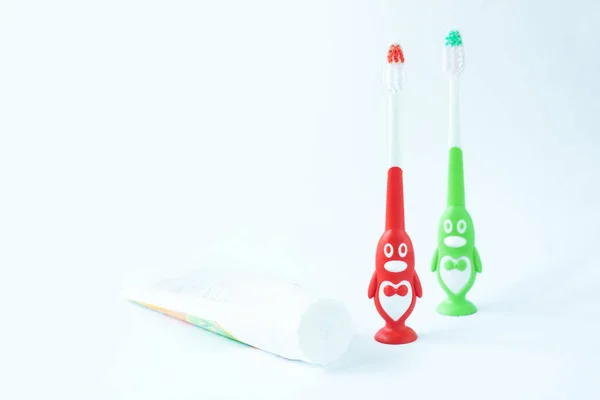 Children's toothbrushes in a form of red and green penguins on a white background isolated. — Stock Photo, Image