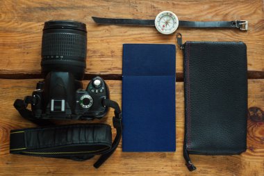 Kamera, uluslararası pasaport, cüzdan ve pusula ile kahverengi ahşap arka plan üzerinde seyahat flatlay.