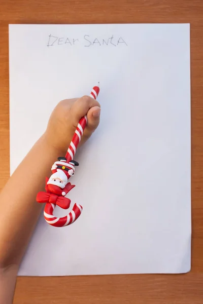 Criança escrevendo carta para o Papai Noel no Natal em casa em uma mesa de madeira na sala de estar. Espaço de cópia, flatlay . — Fotografia de Stock