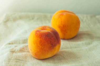 Ahşap masa üzerinde keten bez arka plan üzerinde taze şeftali ile natürmort. Parlak sulu yaz meyveleri, flatlay.