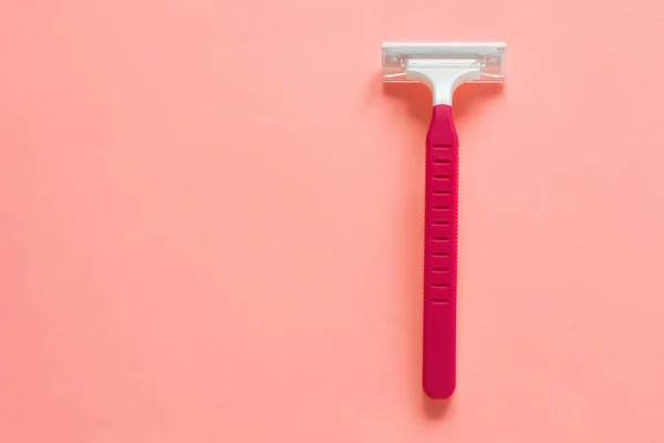 Máquina de barbear descartável para mulheres em um fundo pastel rosa, flatley, espaço de cópia . — Fotografia de Stock