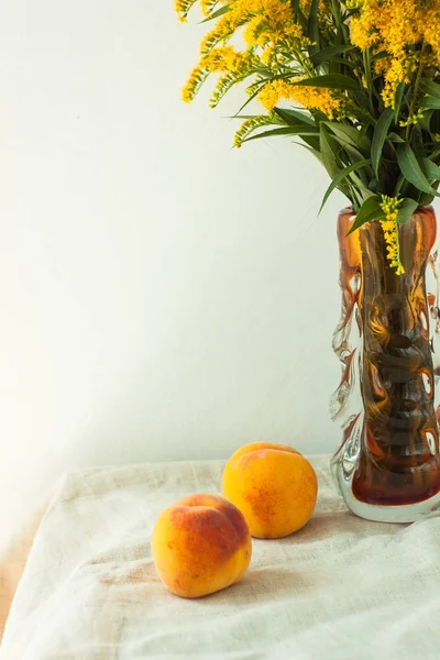 Bodegón con melocotones frescos sobre fondo de tela de lino sobre mesa de madera. Frutas de verano jugosas brillantes con flores amarillas . —  Fotos de Stock