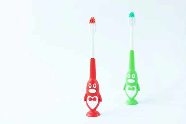 Children's toothbrushes in a form of red and green penguins on a white background isolated. — Stock Photo, Image