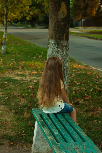 Bir doğa arka plan üzerinde beyaz bir t-shirt uzun sarı saçlı küçük kız. — Stok fotoğraf