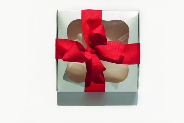 Silberne Geschenkschachtel mit roter Schleife auf weißem Hintergrund. Kopierraum, Flatlay, Draufsicht. — Stockfoto