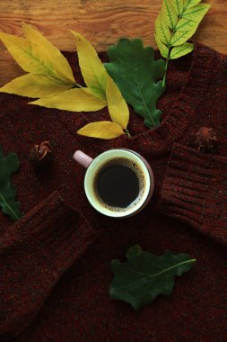 Sonbahar kahvesi. Sonbahar sıcak sağlıklı içecek bir fincan, kahverengi ahşap arka plan üzerinde sıcak yün kazak ile bırakır. Natürmort.