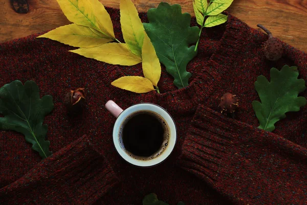 Sonbahar kahvesi. Sonbahar sıcak sağlıklı içecek bir fincan, kahverengi ahşap arka plan üzerinde sıcak yün kazak ile bırakır. Natürmort.