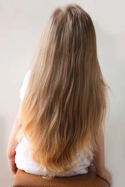 Menina bonito com cabelo loiro longo. Visão traseira da menina olhando para o lado. Isolado em fundo claro . — Fotografia de Stock