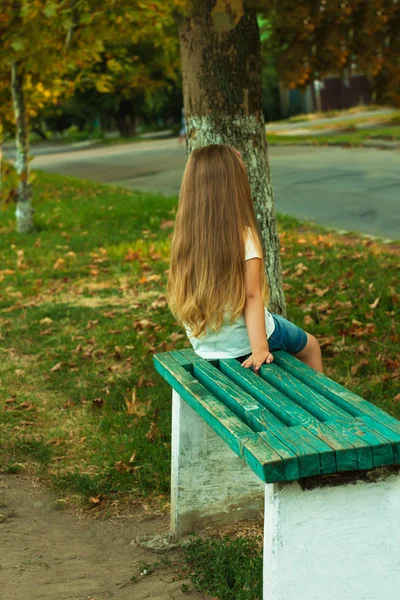 Little girl with long blond hair in a white T-shirt on a nature — Stock Photo, Image