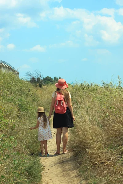 Mother and daughter walking, facing away from camera, enjoying t