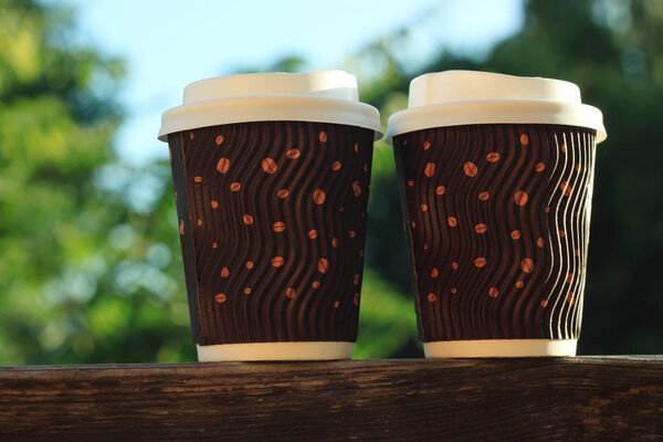 Two coffees to go on the wooden balcony. Lifestyle concept.