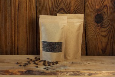 Ahşap bir arka plan üzerinde kahve çekirdekleri ön görünümü ile Kahverengi kraft kağıt kese çanta.