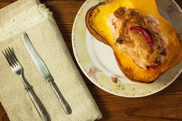 Pumpkin half stuffed with chicken breast and pepper on a wooden background. — Stock Photo, Image