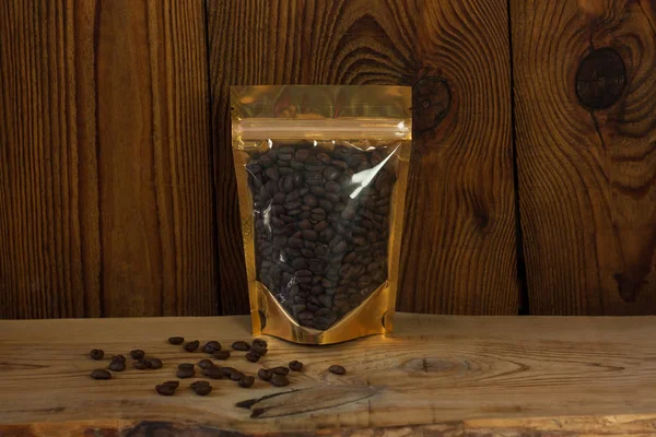 Sacos de bolsa de papel kraft marrom com vista frontal de grãos de café em um fundo de madeira . — Fotografia de Stock